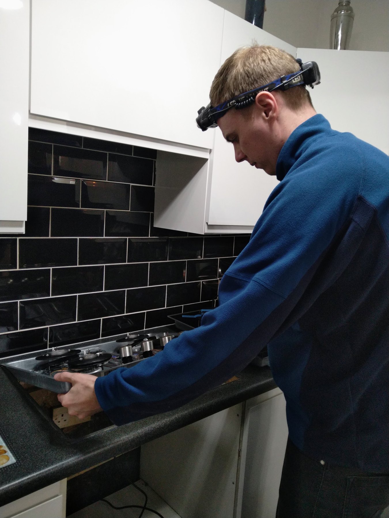 The engineer lowering a hob into a black kitchen worktop
