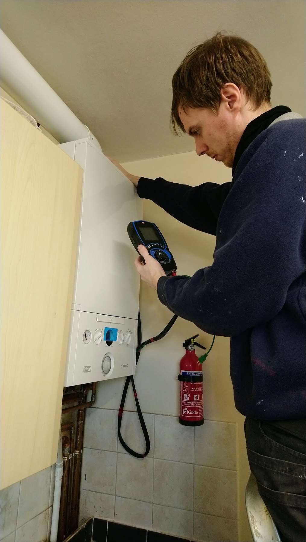 The engineer at a wall-hung boiler with a flue gas analyser in his hand