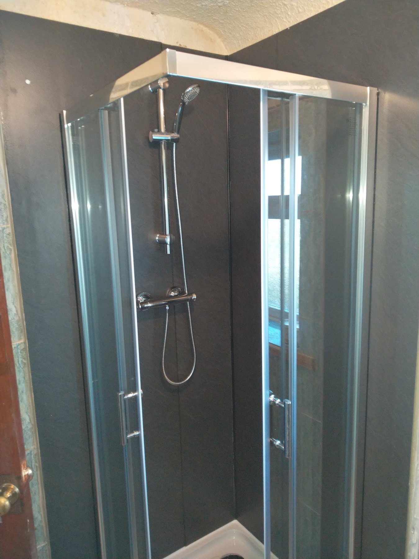 A quadrant shower enclosure with a thermostatic bar shower, seen from the front